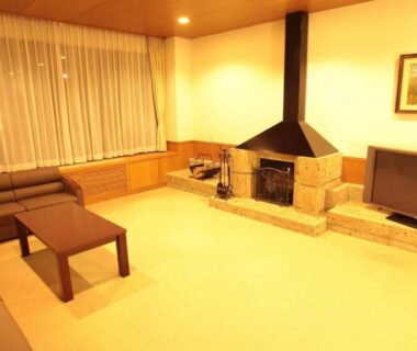 Warm lounge with sofa, low table, fireplace and TV at Resort Project Myoko Kogen in Niigata