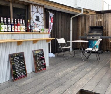 Outdoor wooden terrace with bar counter, stools and chalkboard menus at Riverside Hotel Karatsu Castle Saga