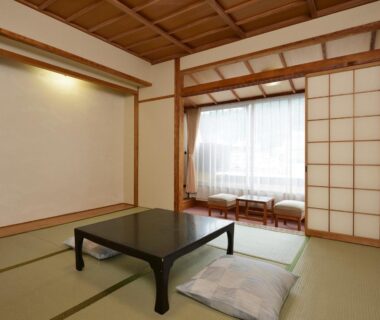 Traditional tatami room with low table, floor cushions and shoji screens at Riverside Uedakan in Nagano