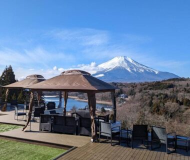 Outdoor terrace with gazebos and seating, deck and lawn, distant snow-capped mountain beyond, Rokumeikan Hills, Yamanashi