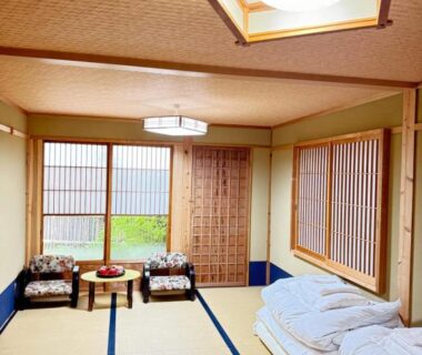 Traditional tatami room with stacked futons, low table and shoji screens at Roman Kan in Kyoto