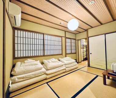 Traditional tatami room with stacked futons, shoji screens and low table at Roman Kan in Kyoto