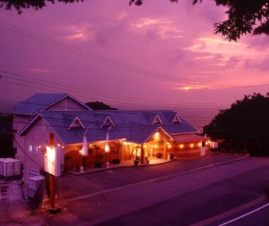 Ryokan exterior at dusk with warm entrance lights and purple twilight sky along roadside in Shizuoka, Chūbu