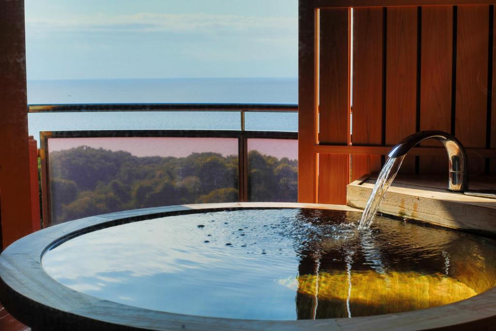 Ocean View Soaking Tub Rurika Shizuoka Wooden soaking tub on balcony overlooking sea and coastal treeline at Rurika ryokan Shizuoka