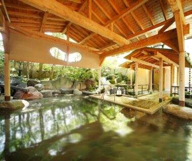 Stone-lined covered onsen with wooden beams and garden surroundings at Rurikoh, Ishikawa, Japan