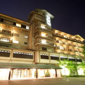 Illuminated multi-story façade of Rurikoh ryokan at night with balconies and lit entrance in Ishikawa, Chūbu, Japan