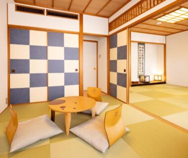 Spacious tatami room with low round table, zaisu chairs and checkerboard fusuma panels at Ryokan Asakusa Shigetsu, Tokyo