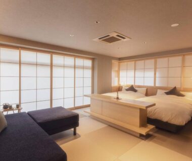 Spacious tatami room with twin beds, shoji screens and seating area at Ryokan Asukasou, Nara Park entrance