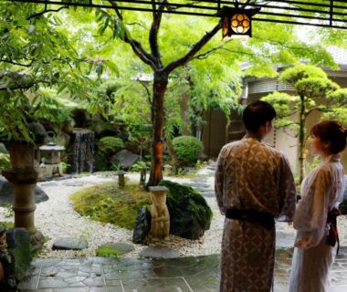 Two guests in yukata viewing a mossy stone garden with lanterns at Ryokan Asukasou, Nara