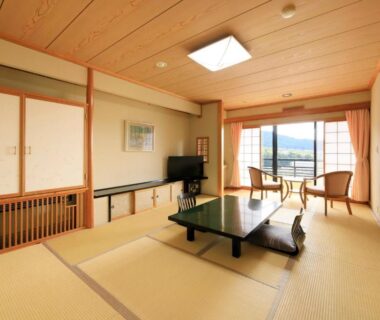Traditional tatami room with low table, zabuton cushions, shoji screens and balcony with distant hills