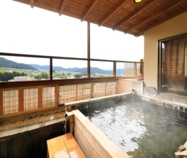 Steaming wooden onsen tub on balcony with mountain views and wooden railing at Ryokan Biyunoyado, Nagano
