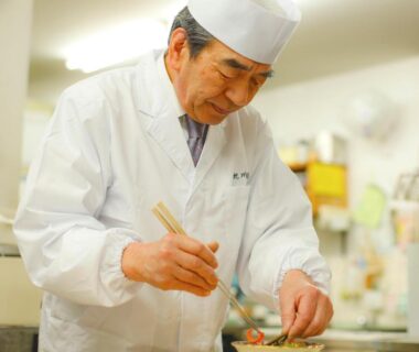 Chef in white uniform plating a dish in Ryokan Chinsen-Rou kitchen, Kyoto