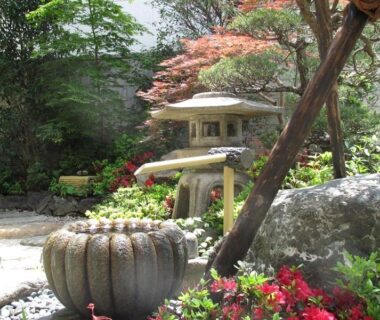Traditional Japanese courtyard garden with stone lantern, water basin and foliage at Ryokan Fuji in Tokyo