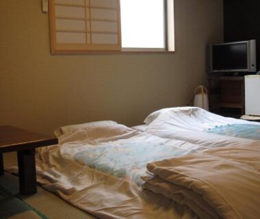 Tatami room with futon bedding, low table and shoji screen at Ryokan Fuji in Tokyo