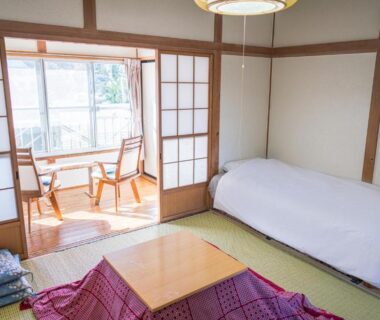 Traditional tatami room with futon, low covered kotatsu table, shoji screens and window seating at Ryokan Fuji Heights Yamanashi