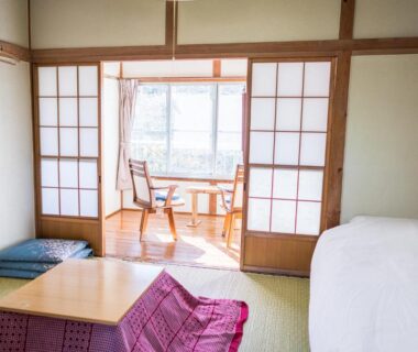 Tatami room with low table, shoji screens and sunlit sitting nook at Ryokan Fuji Heights Yamanashi