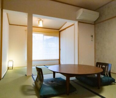 Tatami room with low round table, floor cushions, sliding screen and soft lantern light at Ryokan Fukinoya in Ōita