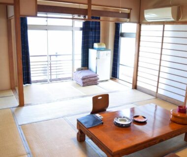 Bright tatami room with low table, folded futons and shoji doors at Ryokan Fukuzen in Gunma, Kantō