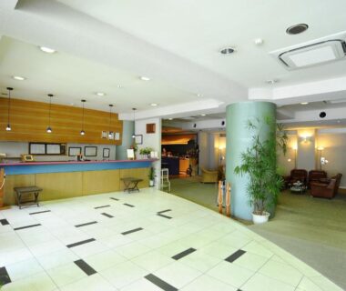 Bright tiled reception lobby with check-in counter, seating and plants at Ryokan Fukuzen, Gunma, Kantō
