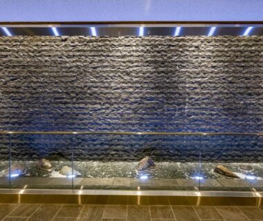 Interior illuminated stone water wall with glass barrier and floor lights at Ryokan Ginkaku Kyoto, Kyoto, Japan