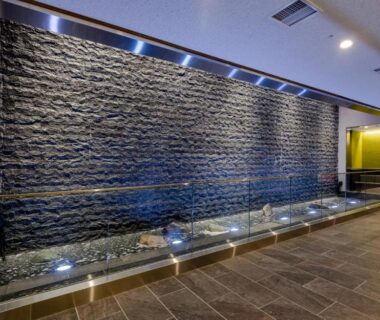 Textured stone water wall with shallow reflecting pool in Ryokan Ginkaku Kyoto lobby, modern tiled interior