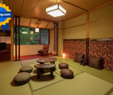 Traditional tatami room with low round table, floor cushions, large window, and warm wooden accents at Ryokan Gizan, Gifu