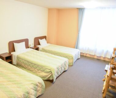 Three single beds in a simple carpeted room at Ryokan HANAEMI, Hokkaidō Japan