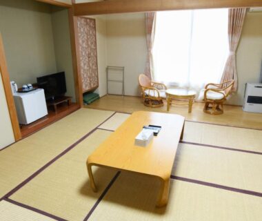 Tatami room with low table, wicker chairs by window at Ryokan HANAEMI in Hokkaidō Japan