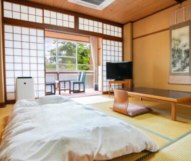 Traditional tatami room with futon, low table, shoji screens and balcony at Ryokan Hirayama in Kumamoto, Kyūshū