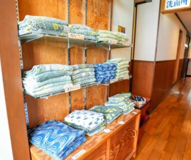 Stacked guest yukata on wooden shelves in Ryokan Hirayama hallway, Kumamoto, Kyūshū