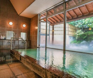 Stone indoor bath with washing stations and garden view at Ryokan Hirayama in Kumamoto, Kyūshū