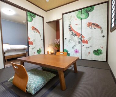 Tatami room with low table, zaisu chairs and koi-decorated sliding fusuma at Ryokan Hitaya, Ōita