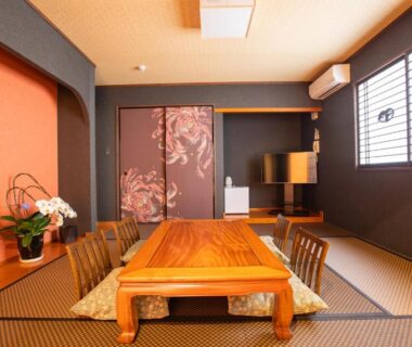 Tatami room with low wooden dining table, shoji windows and decorative sliding panels at Ryokan Hitaya in Ōita