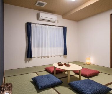 Tatami room with low round table, zabuton cushions and soft lamp lighting at Ryokan Ichinao Tokyo