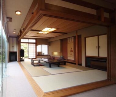 Spacious tatami room with low table, shoji screens, wooden ceiling and garden-facing glass at Ryokan Ichinomatsu, Hokkaidō