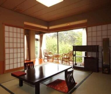Traditional tatami room with low table, zabuton cushions, shoji screens and garden-facing sliding doors at Ryokan Ichinomatsu in Hokkaidō