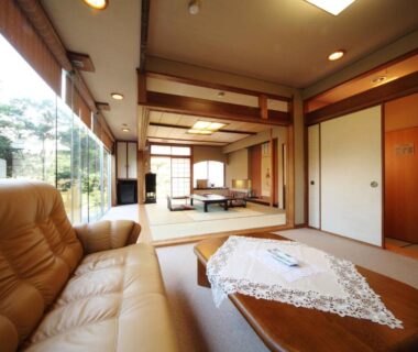 Calm tatami room with low table, sofa seating and sliding shoji doors at Ryokan Ichinomatsu Hokkaidō