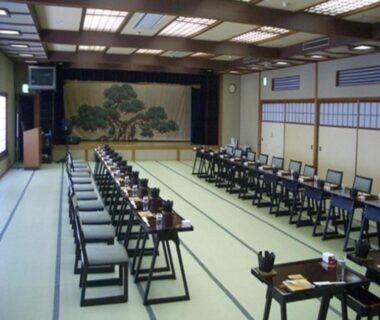 Spacious tatami banquet room with low tables and stage at Ryokan Ichinomatsu in Hokkaidō