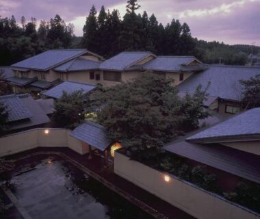 Cluster of tiled rooftops and courtyard reflecting pool under dusk sky in Niigata