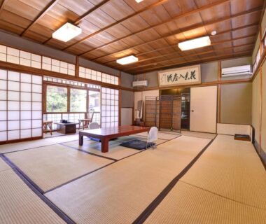 Traditional tatami room with low wooden table, shoji screens and garden view at Ryokan Inakatei, Kyoto