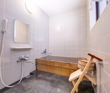 Tiled bathing area with wooden tub, shower and stool at Ryokan Inakatei in Kyoto Kansai