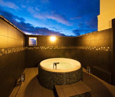Circular outdoor tiled bath with evening sky at Ryokan KANADE, Kyoto