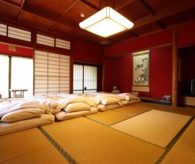 Traditional tatami room with futon bedding, shoji screens and hanging scroll at Ryokan Karasawa in Ishikawa