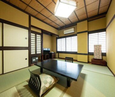 Traditional tatami room with low table and zabuton cushions, shoji screens at Ryokan Kiraku in Oita, Kyushu