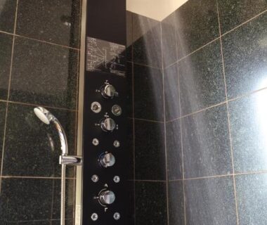 Tall black shower panel with overhead rainhead, body jets and handheld in a Ryokan Kono-Yu bathroom, Kumamoto, Kyūshū
