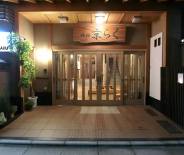 Wooden sliding doors, tiled foyer and potted plants at Ryokan Kyoraku in Kyoto