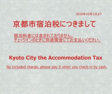 Bilingual red text notice about Kyoto City accommodation tax displayed at Ryokan Kyoraku in Kyoto