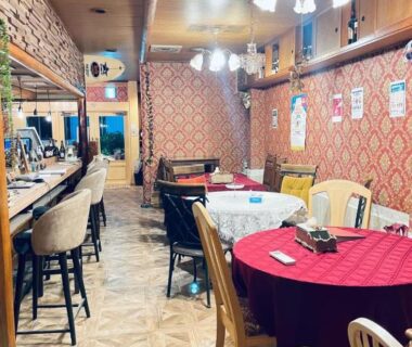 Dining area with round tables, bar counter, chandeliers and patterned wallpaper at Ryokan La Luna in Shizuoka