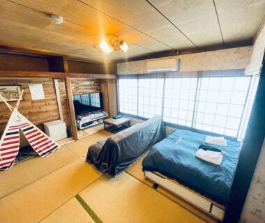 Spacious tatami room with futon beds, shoji screens, low table and wooden interior at Ryokan La Luna in Shizuoka