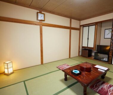 Traditional tatami room with low table, zabuton cushions, shoji screens, floor lamp and TV cabinet at Ryokan Matsushima Kanagawa
